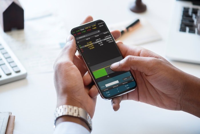 businessman holding a cellphone and checking trading