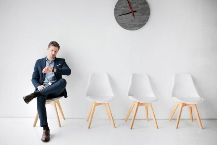 man waits patiently looking at his watch