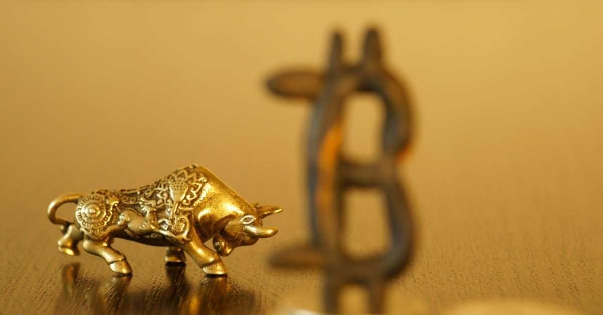 A golden bull next to a bitcoin logo